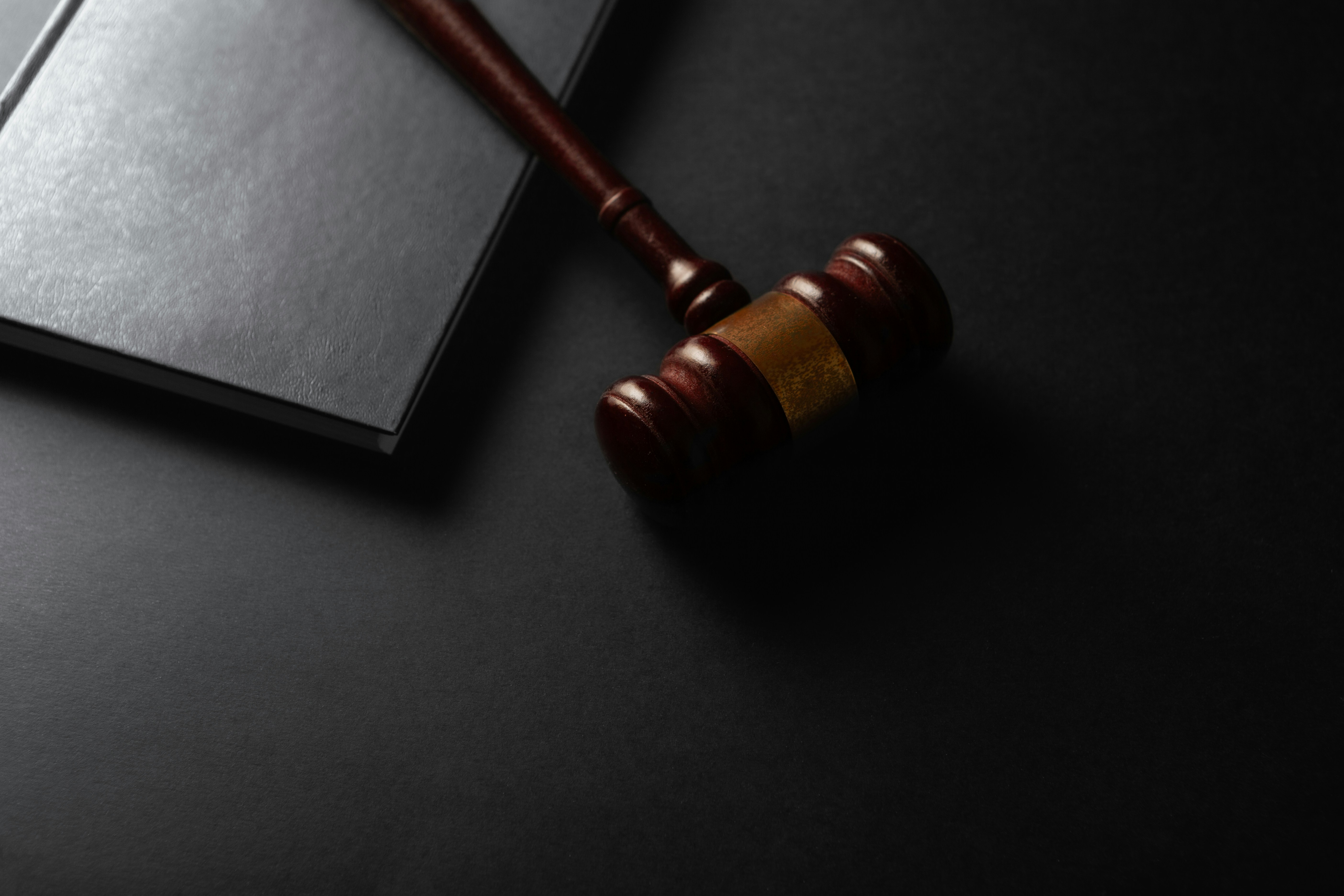 A gavel resting on a desk in a dark courtroom